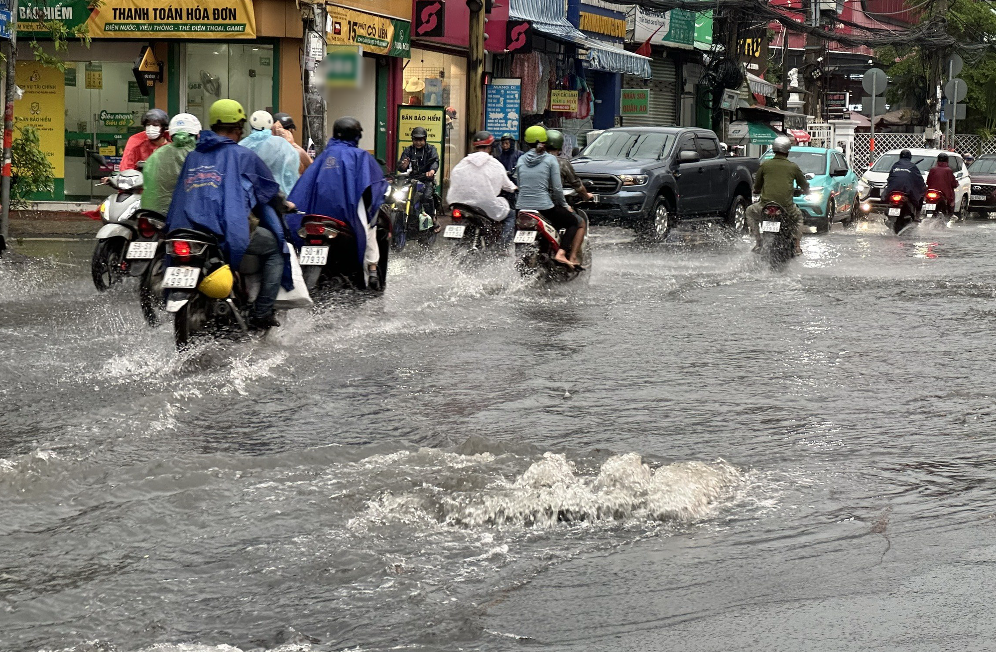 Mưa khiến nước trào lên miệng cống ở đường Lê Văn Việt (TP Thủ Đức) - Ảnh: NGỌC QUÝ