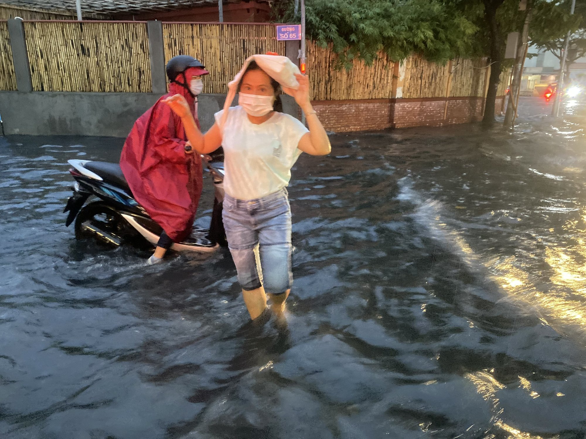 Nước dâng cao tại tuyến đường Quốc Hương (TP Thủ Đức), người dân xắn quần lội nước đi lại - Ảnh: TIẾN QUỐC